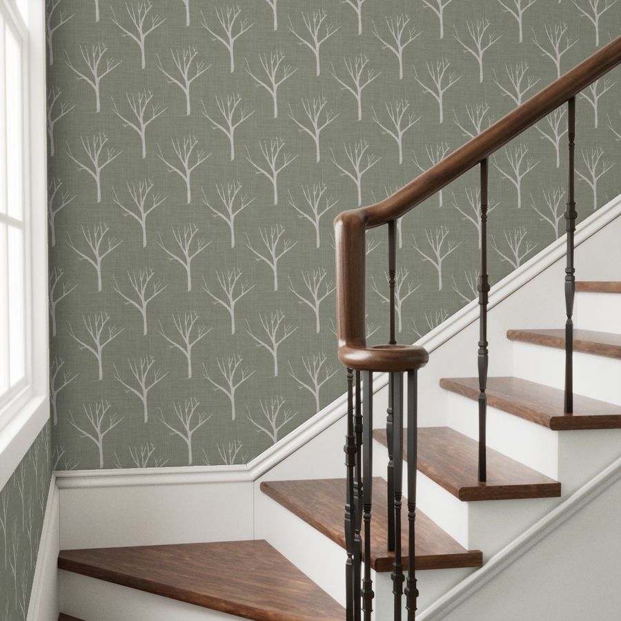 Staircase with wooden steps and a brown railing against a wall with tree-patterned wallpaper.